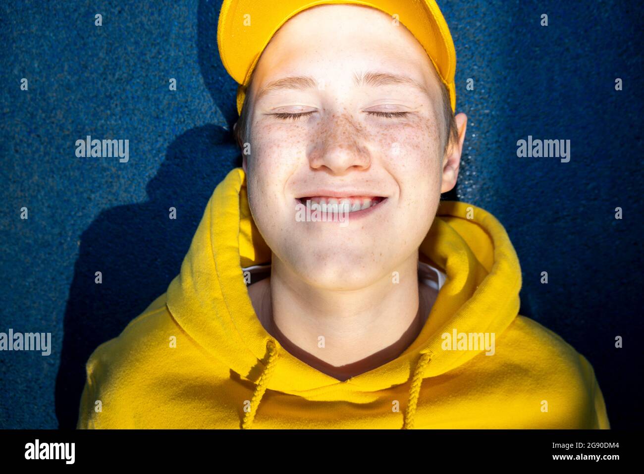 Boy in yellow sweatshirt smiling with eyes closed Stock Photo