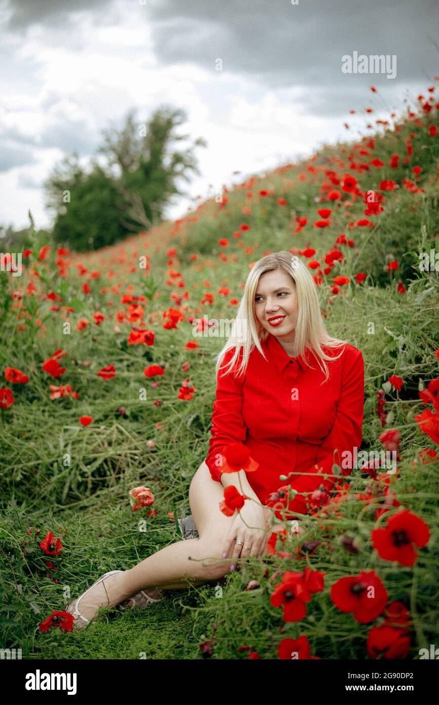 beautiful girl in a field with red poppies in a red shirt Stock Photo ...