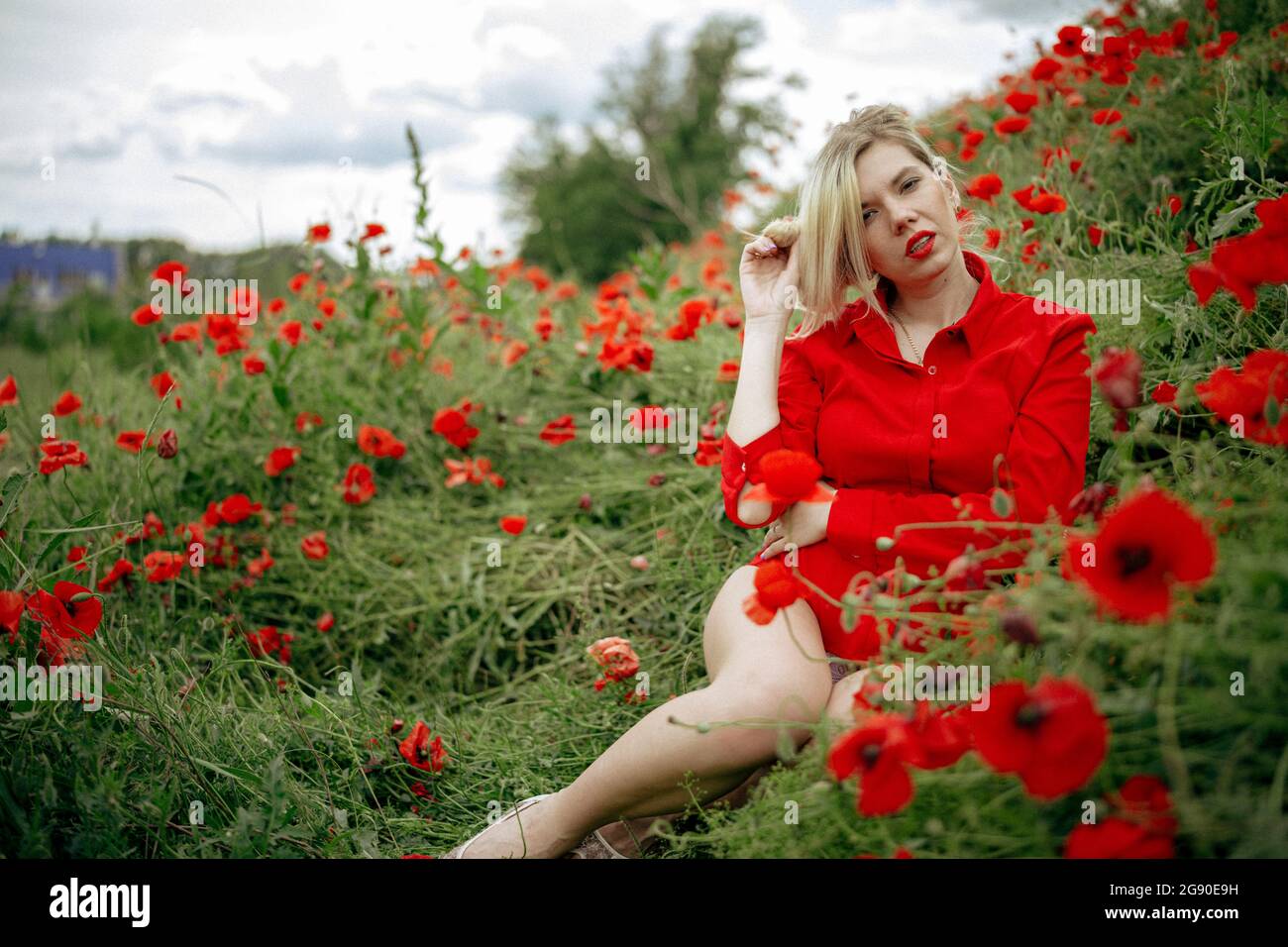beautiful girl in a field with red poppies in a red shirt Stock Photo ...