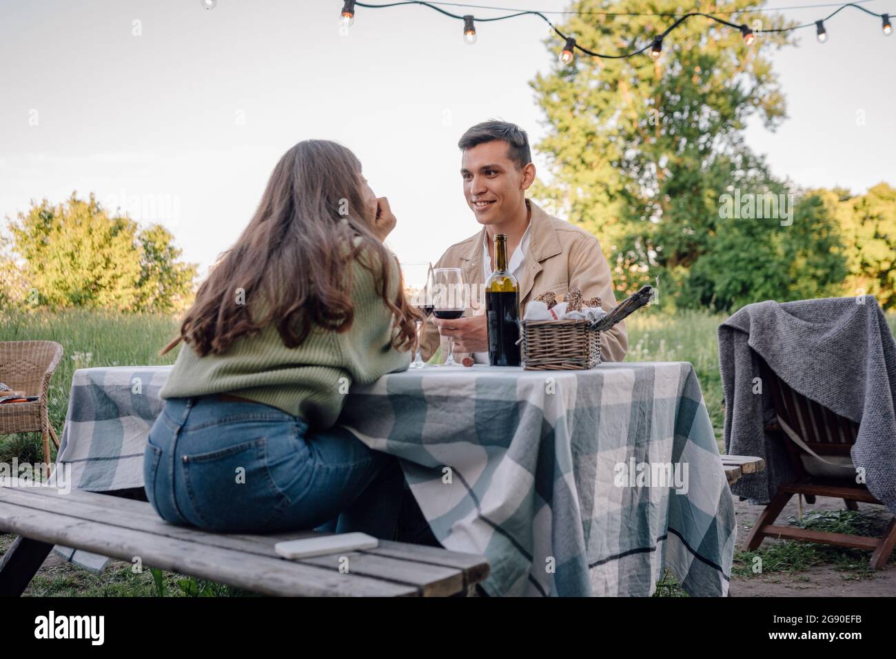 Smiling young man looking girlfriend sitting on bench Stock Photo