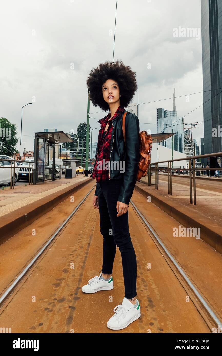 Woman with backpack standing on railroad track Stock Photo