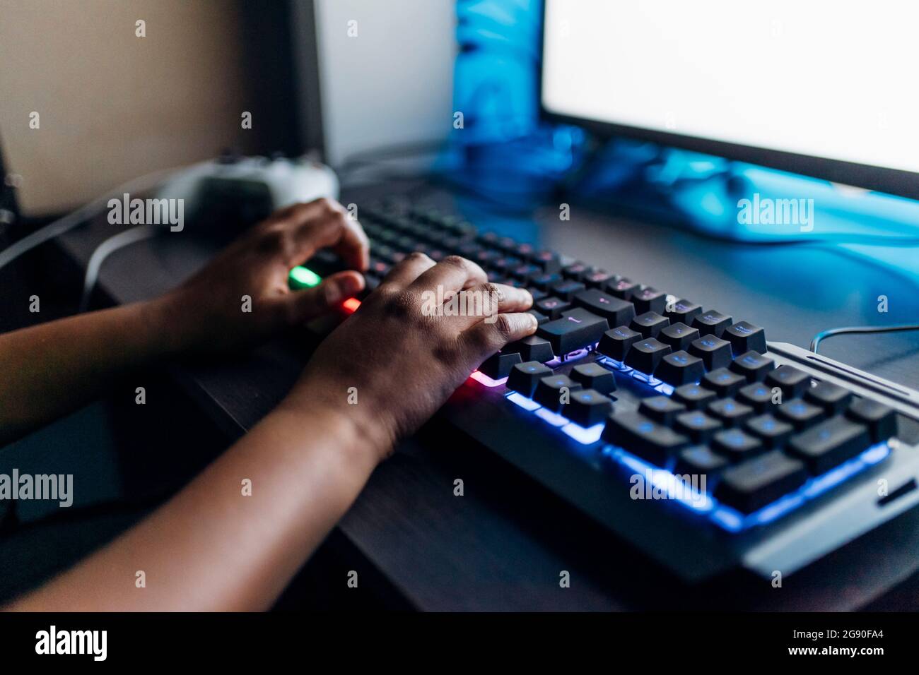 Boy playing game on computer through illuminated keyboard at home Stock Photo