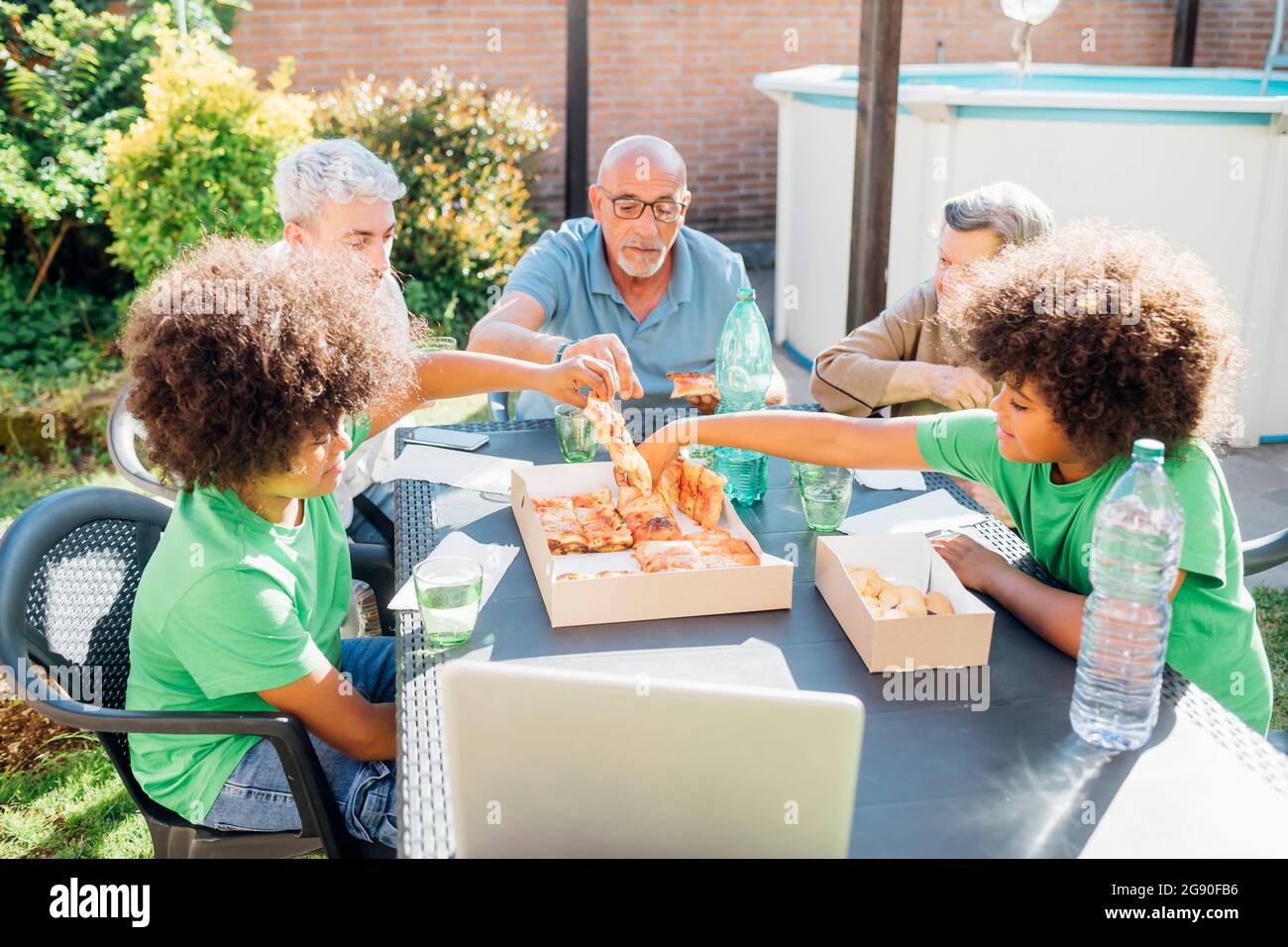 Multi-ethnic family enjoying snacks on table in back yard Stock Photo