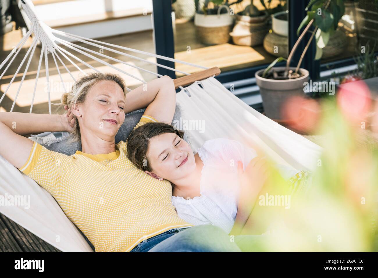 Woman and girl napping together in hammock Stock Photo