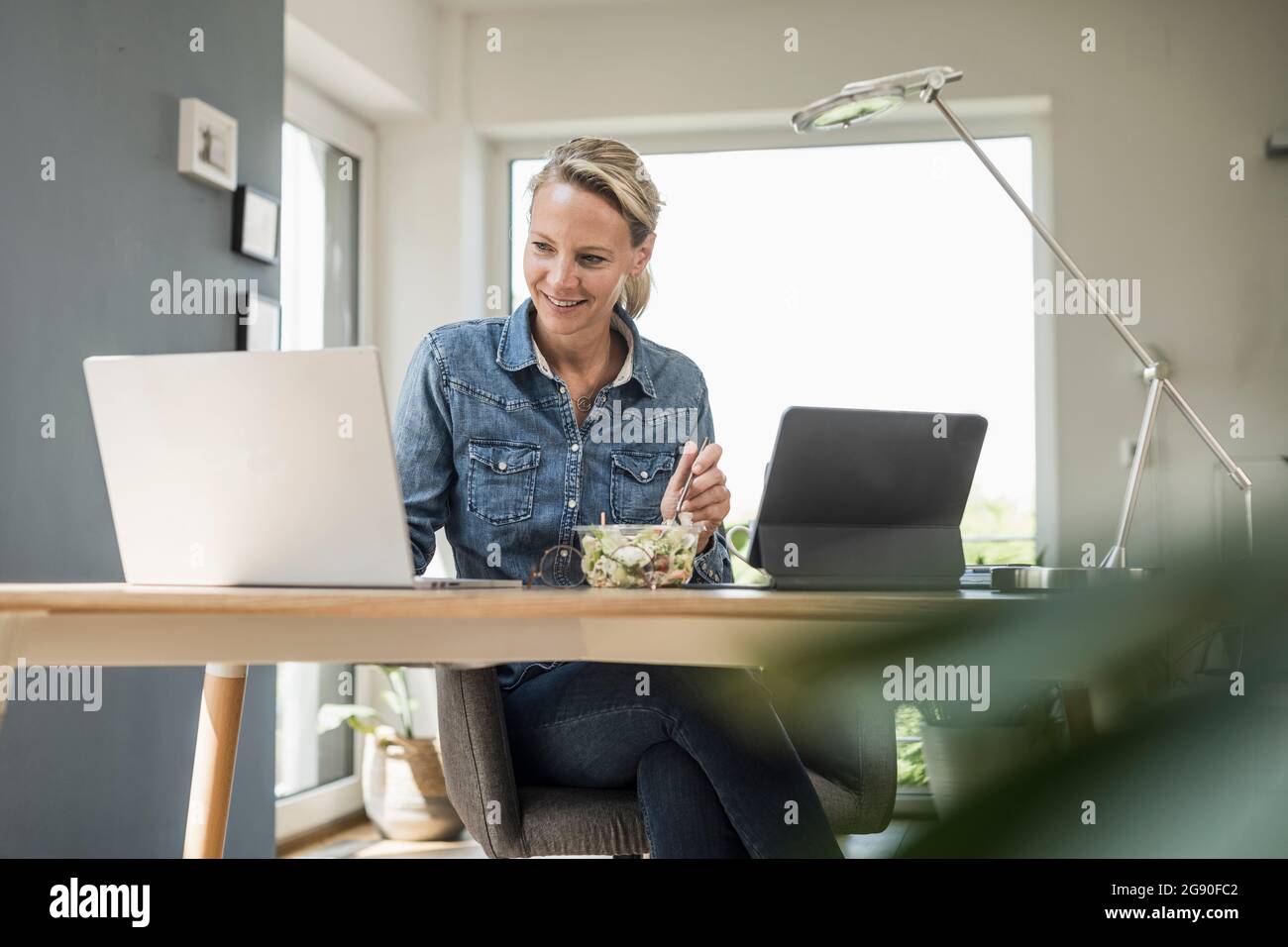 Female freelance worker using laptop while sitting at home office Stock Photo