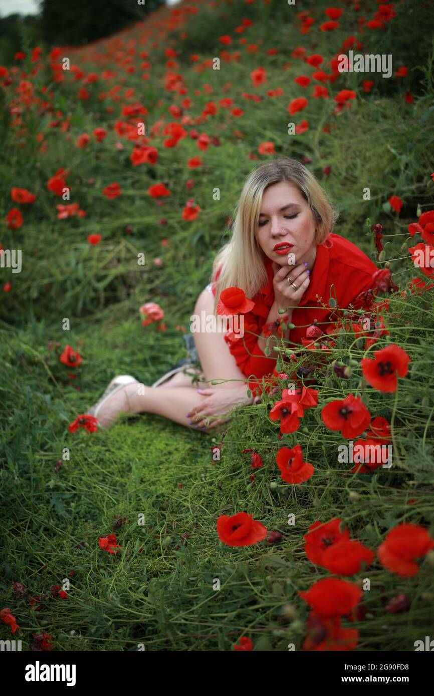 beautiful girl in a field with red poppies in a red shirt Stock Photo ...