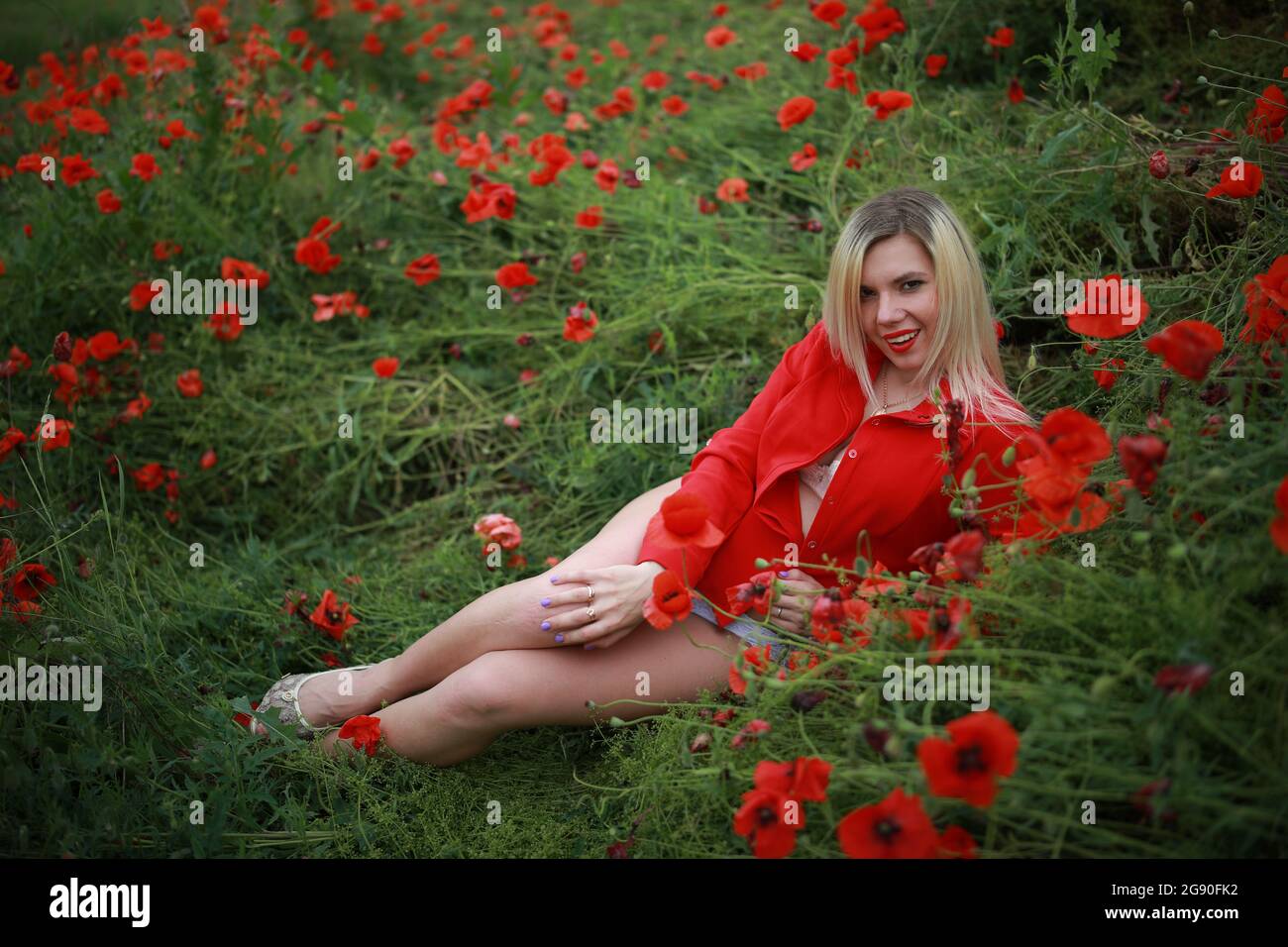 beautiful girl in a field with red poppies in a red shirt Stock Photo ...