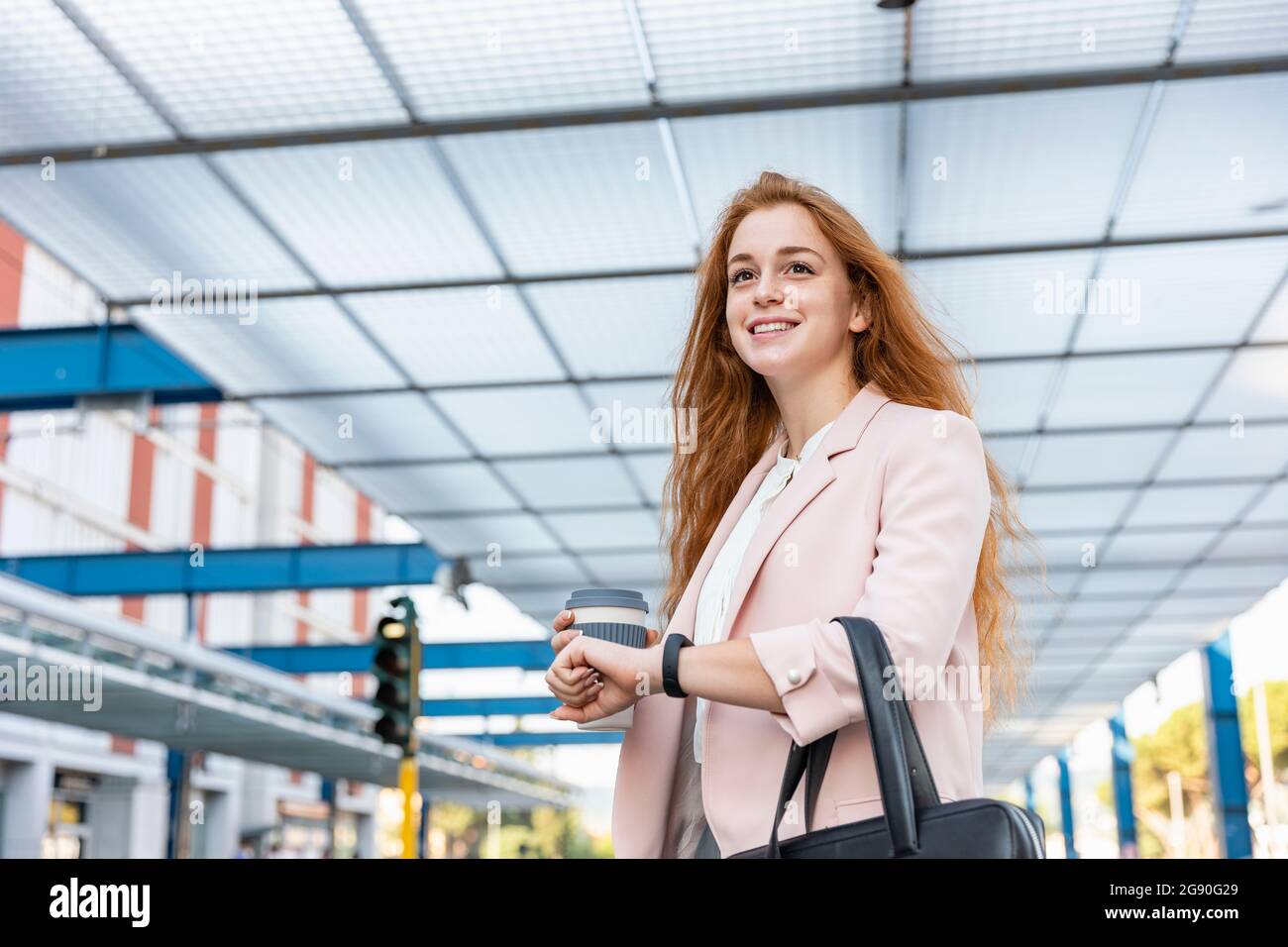 Smiling female professional looking away while waiting on platform Stock Photo