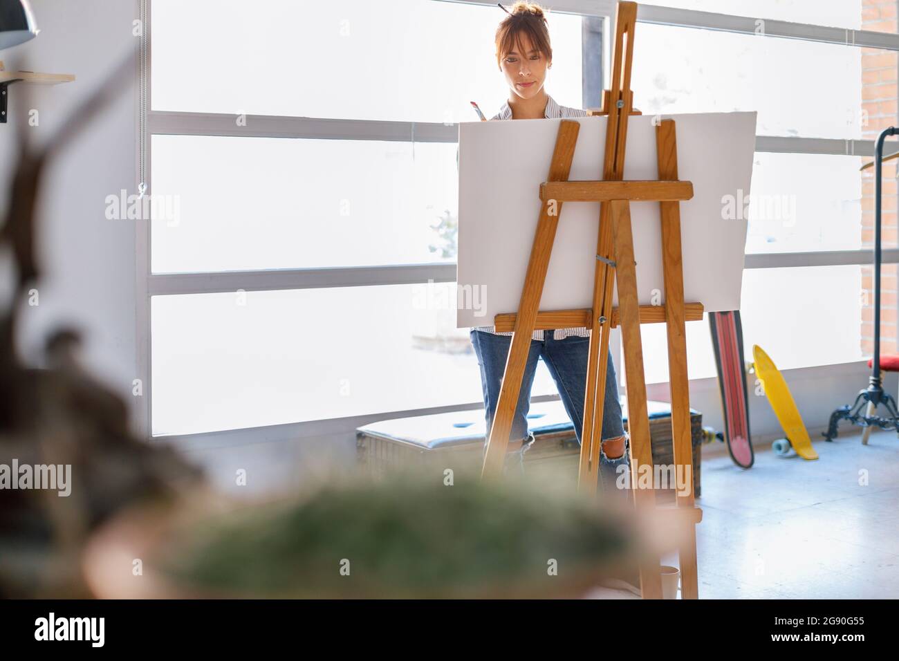 Female painter standing behind easel in studio Stock Photo - Alamy