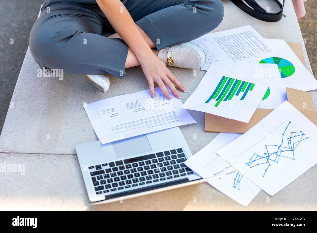Businesswoman analyzing data in front of laptop on bench Stock Photo