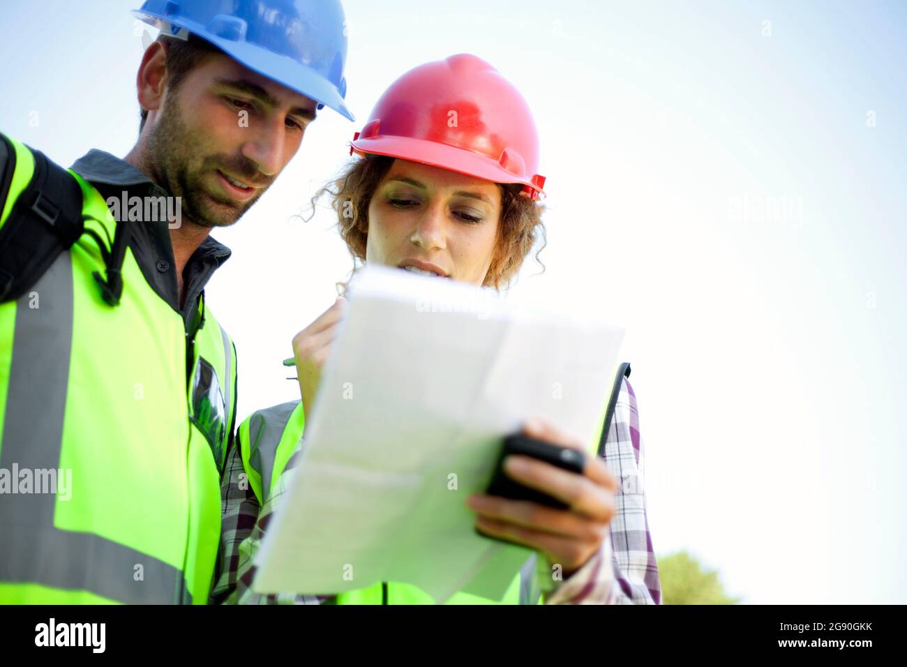 Male and female engineers discussing while holding document Stock Photo