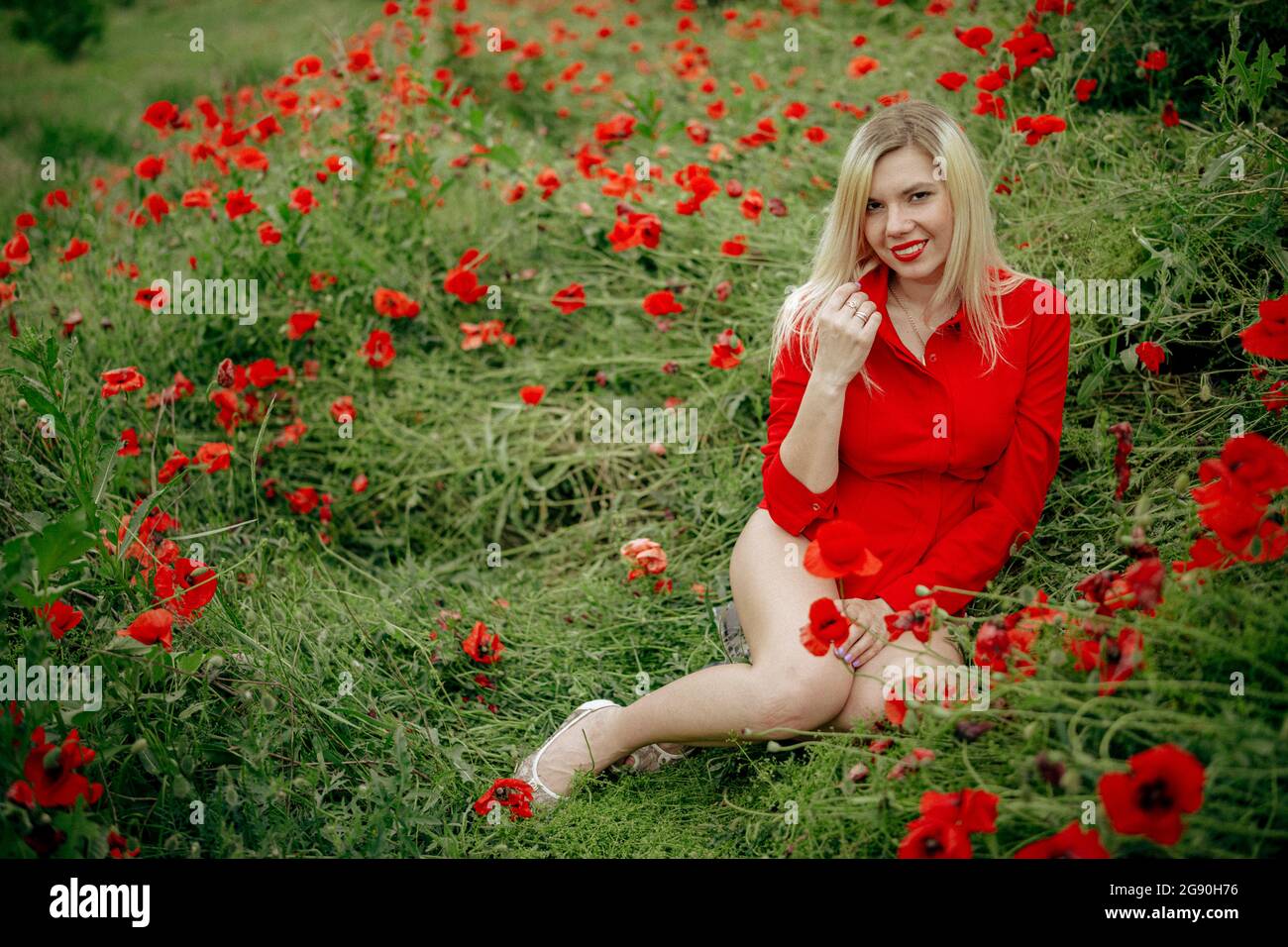 beautiful girl in a field with red poppies in a red shirt Stock Photo ...