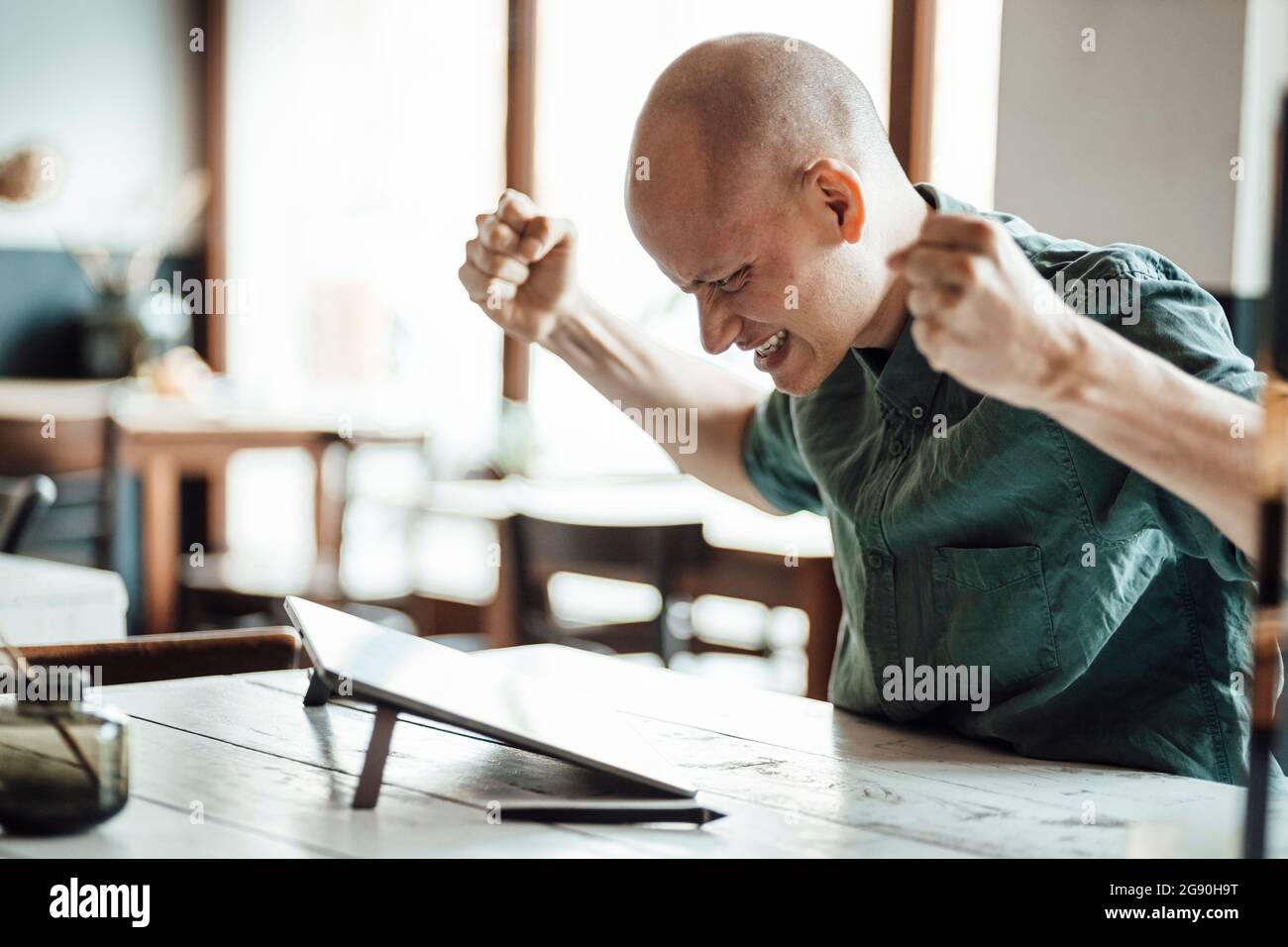 Bald male design professional cheering in excitement while looking at graphics tablet Stock Photo