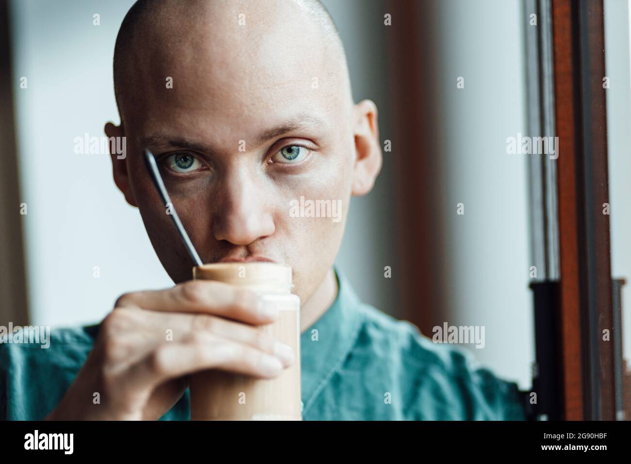 Male cafe owner staring while drinking coffee Stock Photo