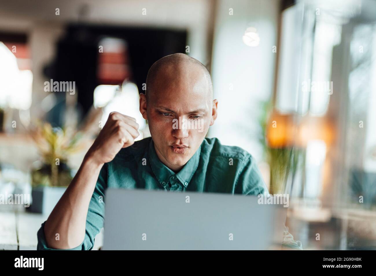 Male cafe owner cheering while using laptop Stock Photo