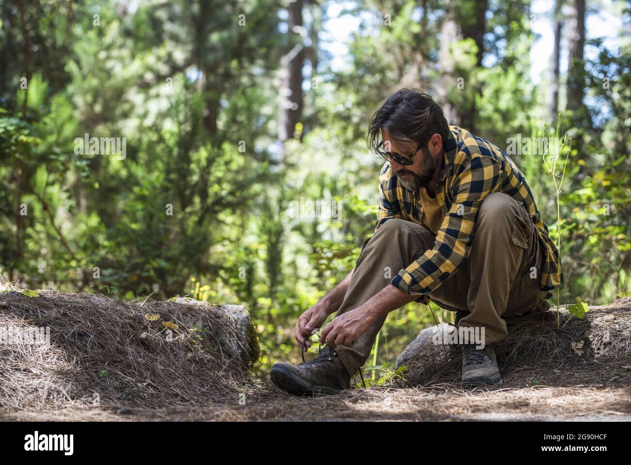 Mature man tying shoelace in forest Stock Photo