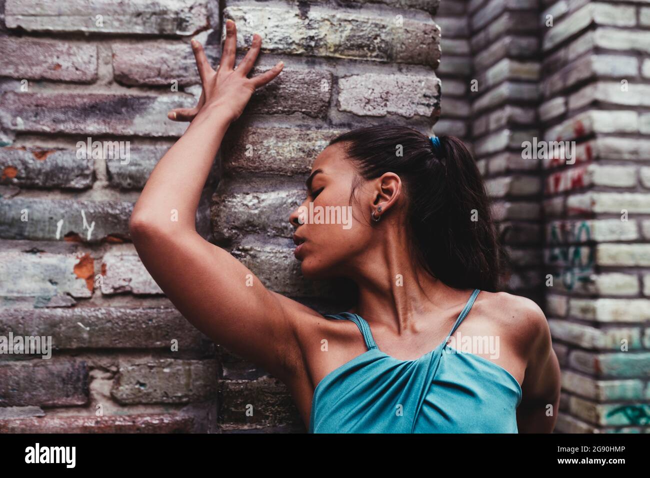 Young female dancer with eyes closed in front of stone wall Stock Photo