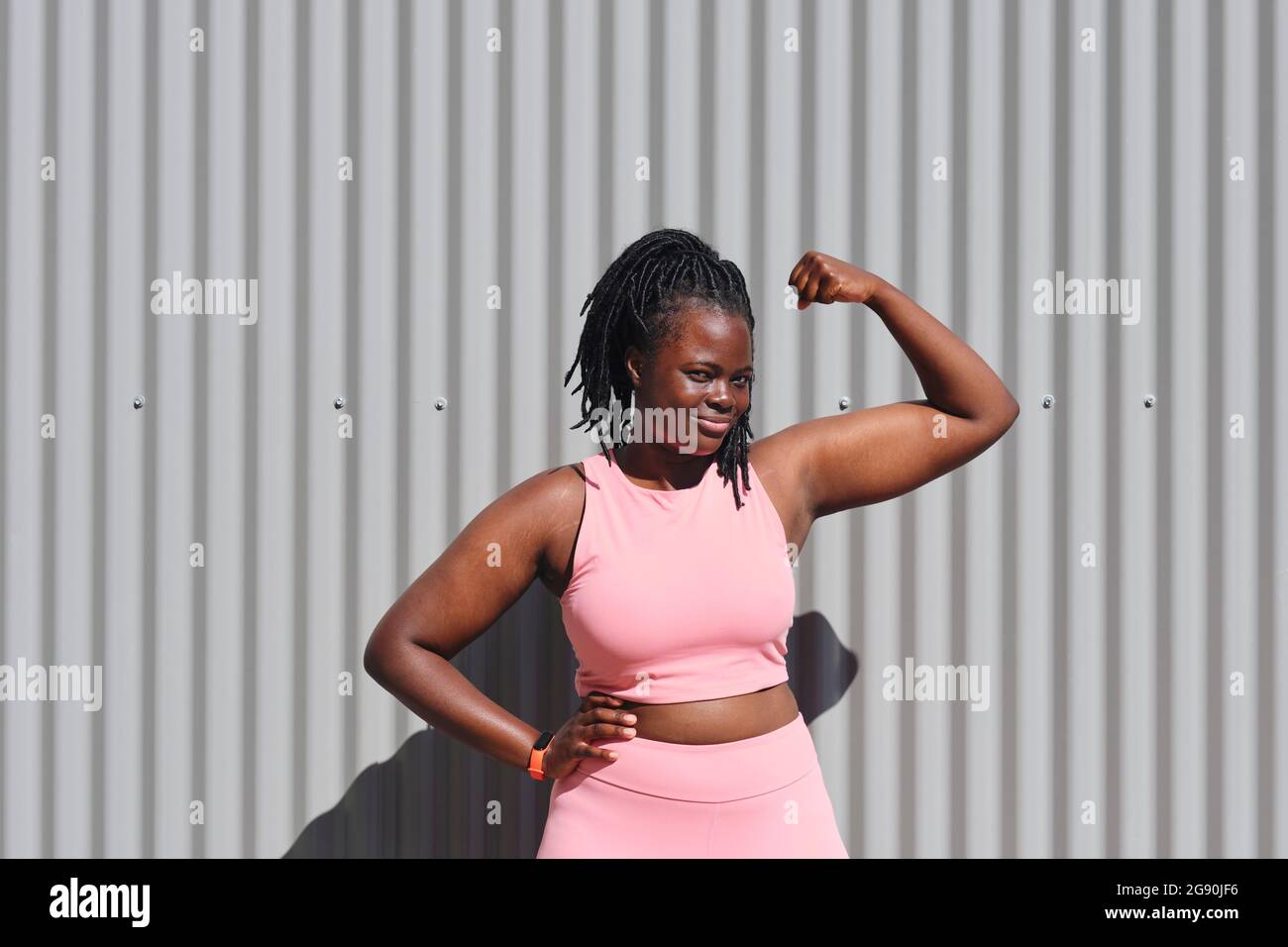 Young woman flexing biceps on sunny day Stock Photo