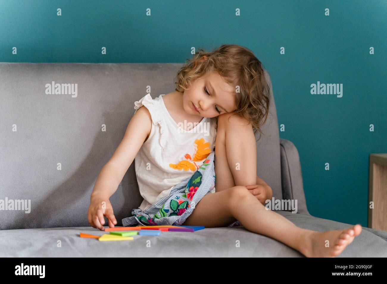 Cute girl playing with toy while sitting on sofa at home Stock Photo