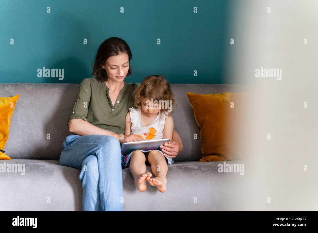 Mother helping daughter using digital tablet while studying at home Stock Photo