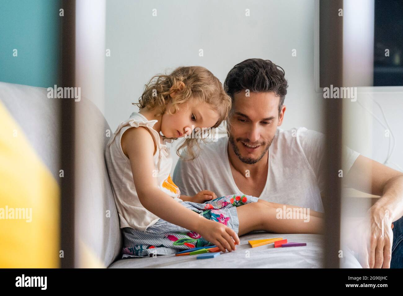 Girl arranging puzzle while sitting with father at home Stock Photo