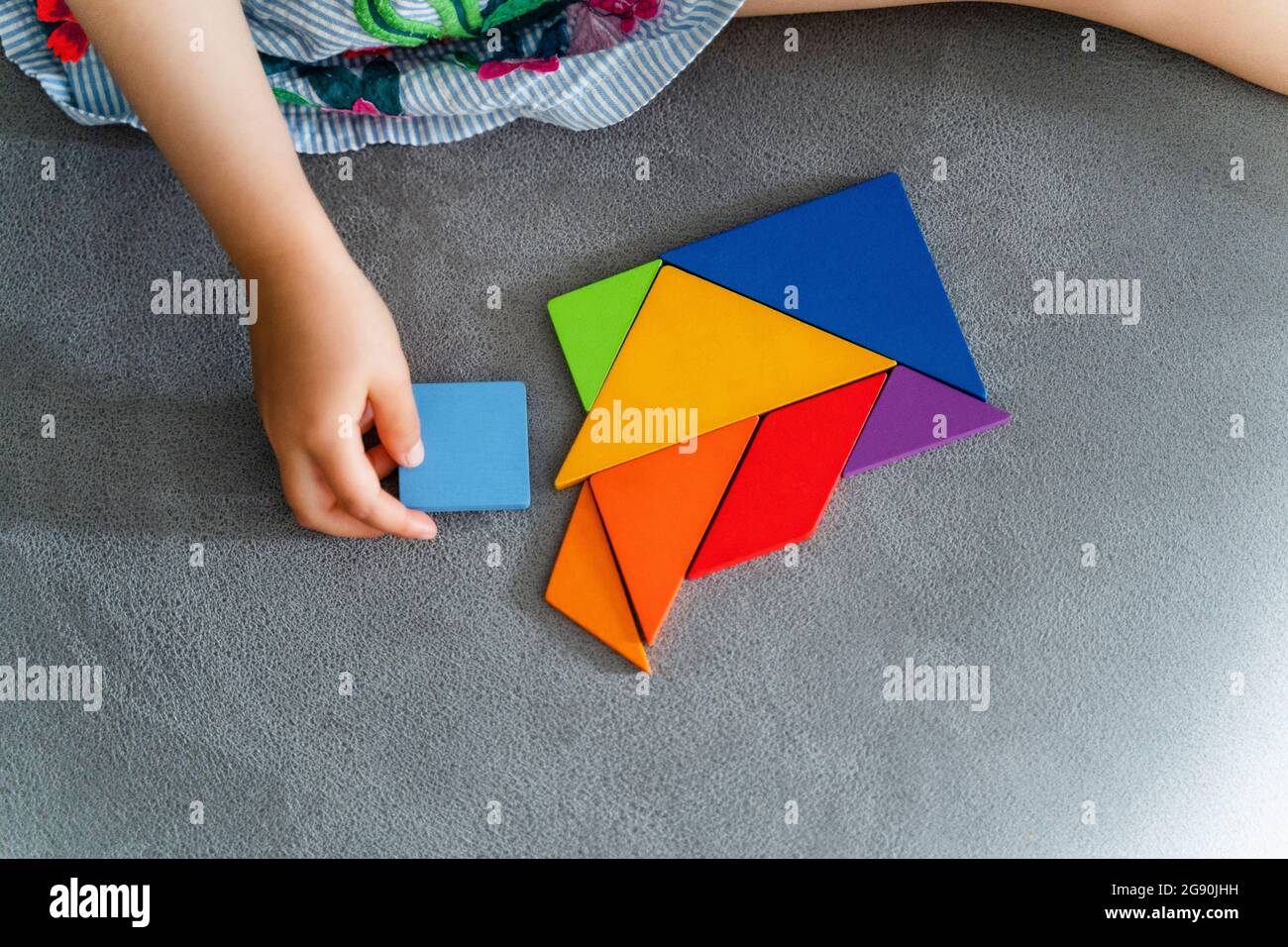 Woman playing with multi colored tangram on sofa Stock Photo