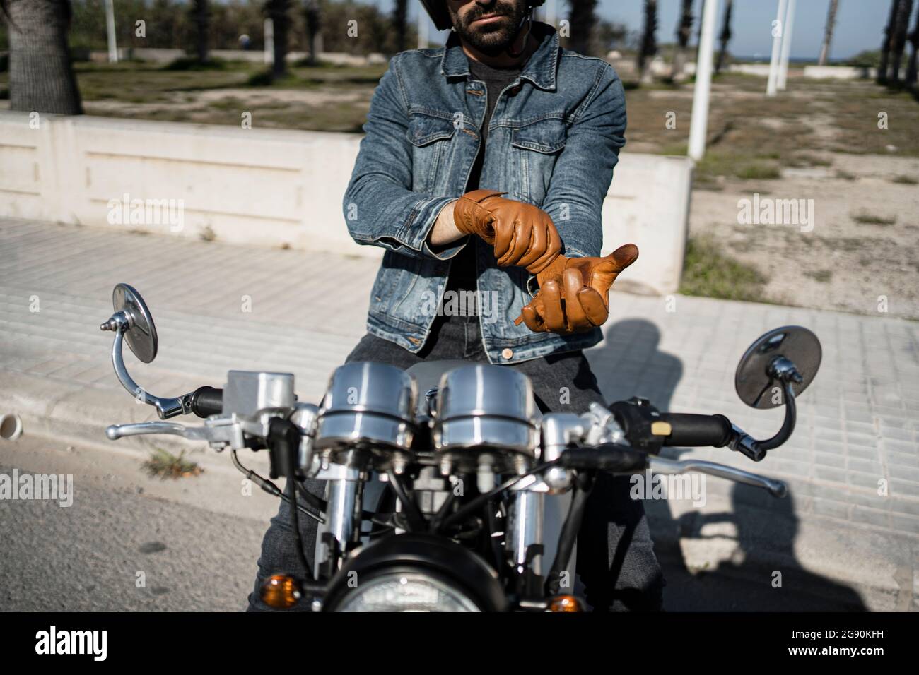 Young man wearing gloves while sitting on motorcycle Stock Photo