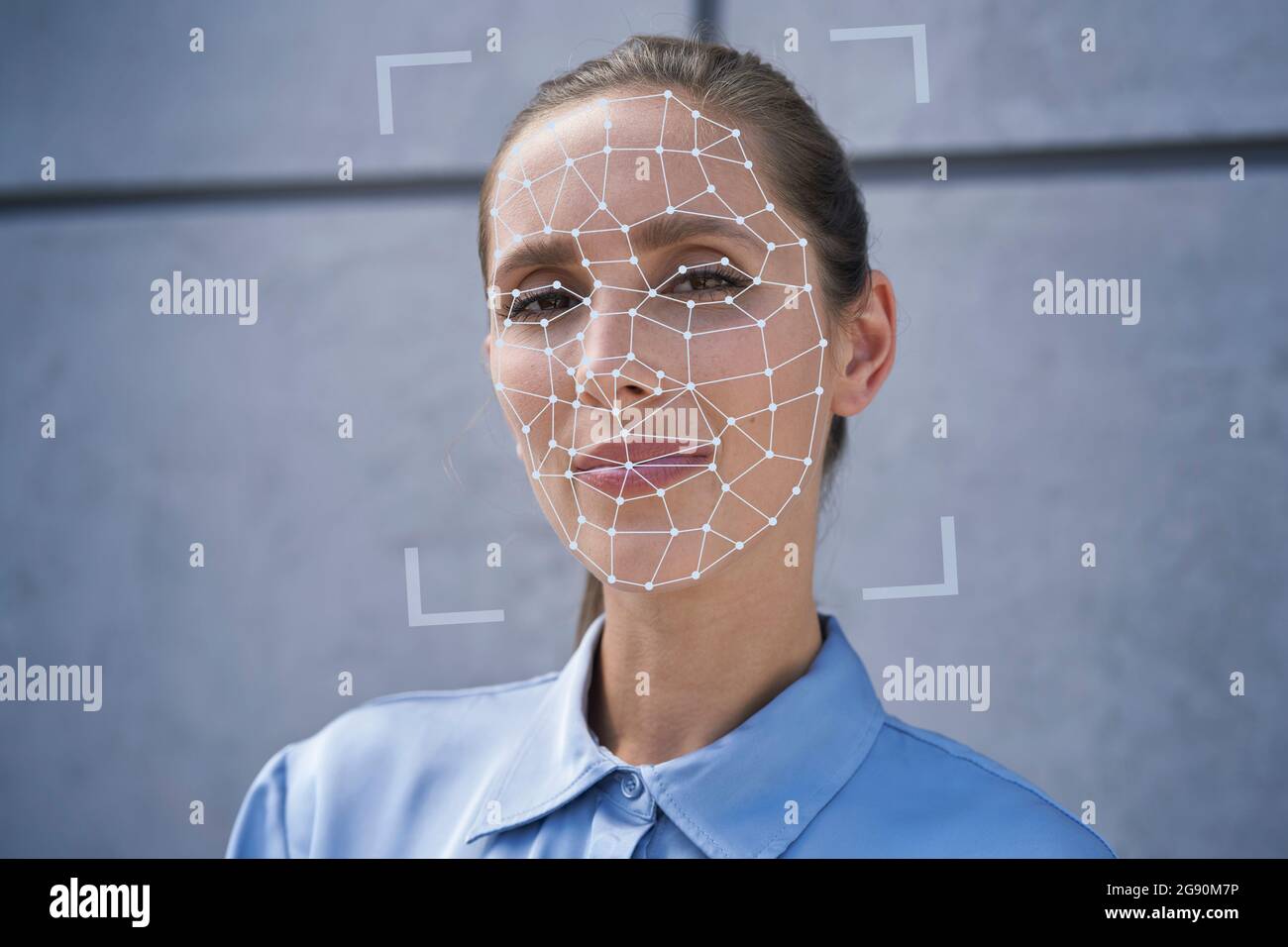 Businesswoman with facial recognition biometrics in front of wall Stock Photo