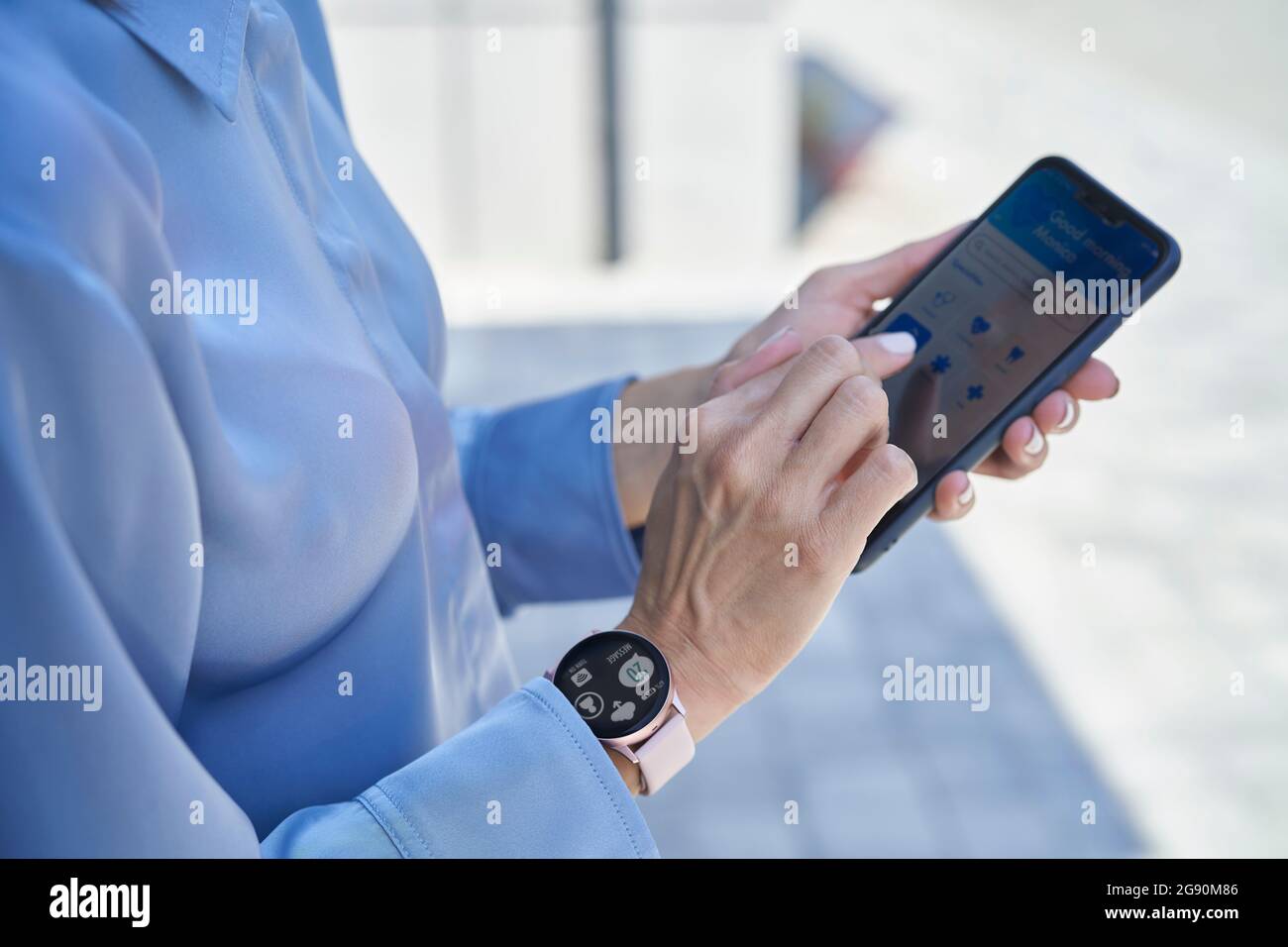 Businesswoman with smart wristwatch using mobile phone Stock Photo