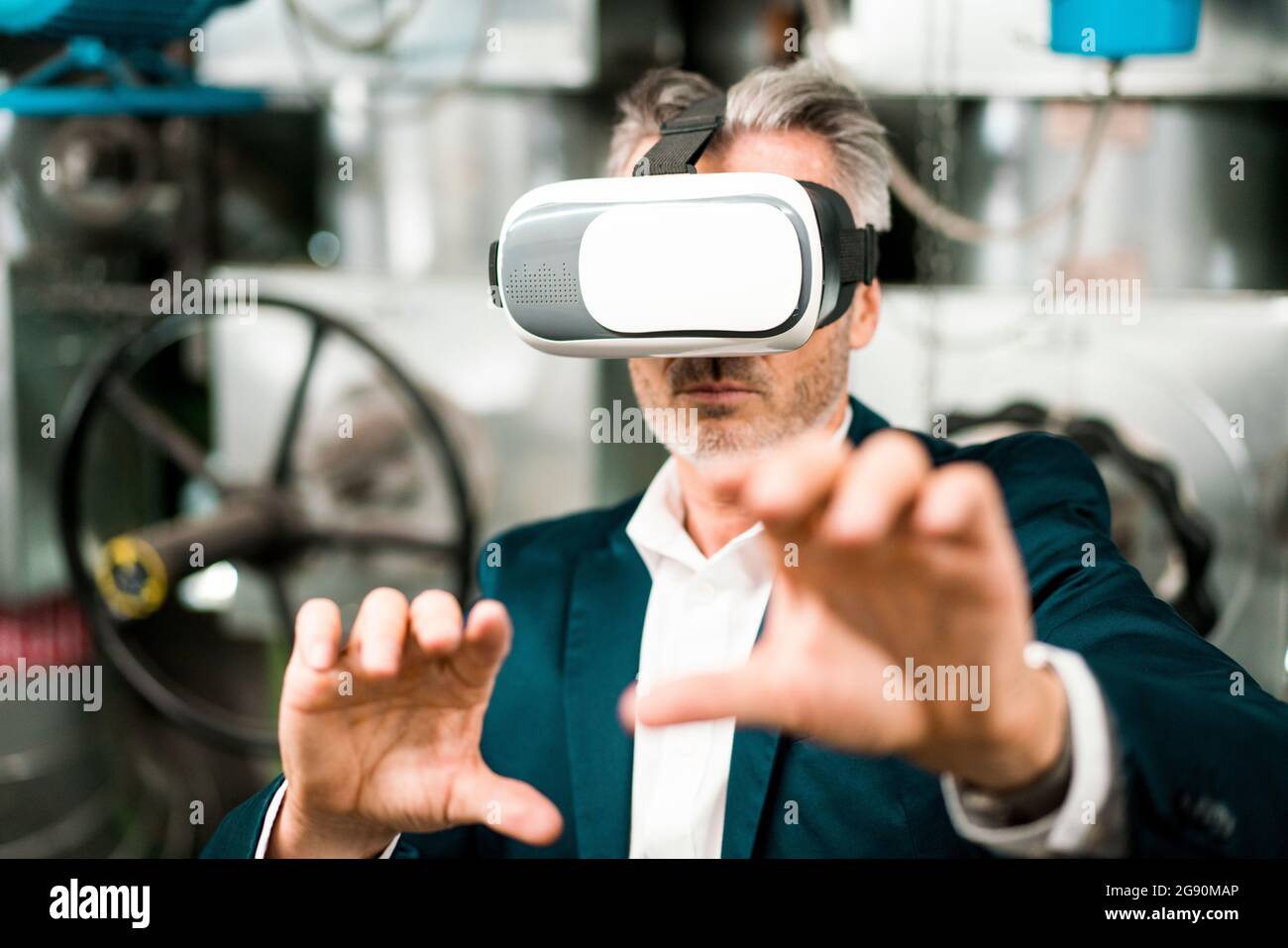 Businessman gesturing while using virtual reality headset at workshop Stock Photo