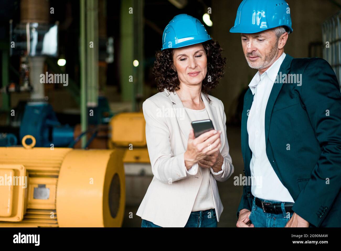 Inspector team with hardhat using mobile phone while standing in industry Stock Photo