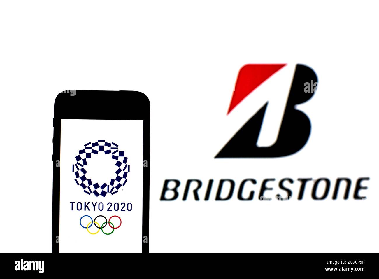 In this photo illustration a Tokyo 2020 Olympic Games logo seen displayed on a smartphone with a Bridgestone logo in the background. Stock Photo