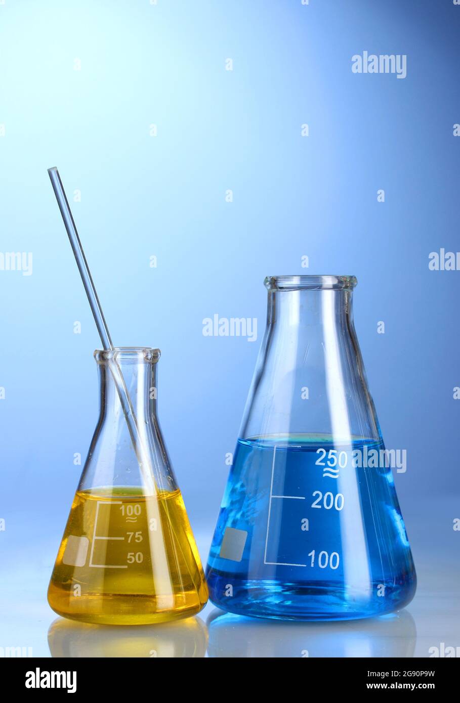 Two flasks with yellow and blue liquid with reflection on blue ...