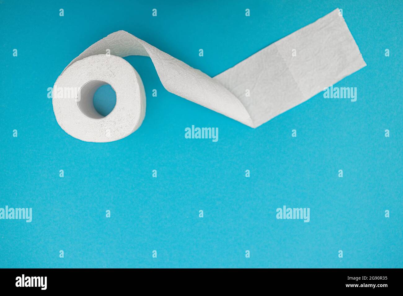 A roll of white toilet paper on a blue background. View from above. Copy space Stock Photo