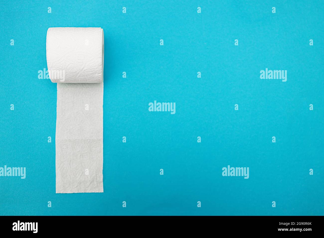 A roll of white toilet paper on a blue background. View from above. Copy space Stock Photo