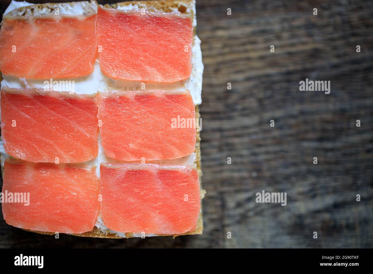 Whole grain bread toasts with cream cheese and lightly salted salmon on a dark wooden board. Flat lay. Copy space. Concept, healthy breakfast, food, s Stock Photo