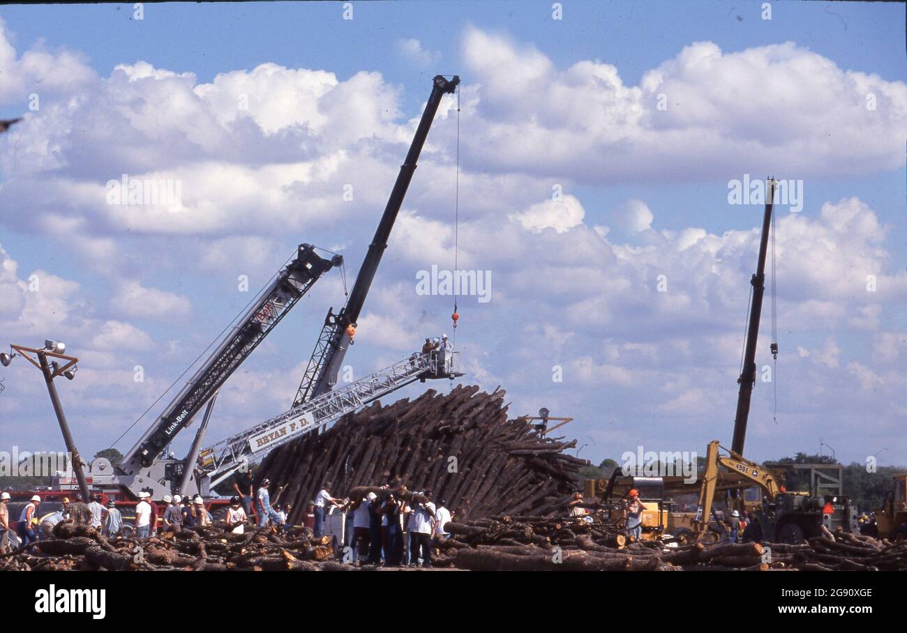 College Station Texas USA, November  18 1999: Crane operators join students and other volunteers remove logs from the huge piles of timber just hours after the Aggie Bonfire collapse that killed 12 people building the stacks. Bonfire is a student-led ritual at the campus that has been part of school spirit activities leading up to the annual Texas-Texas A&M football game for decades. ©Bob Daemmrich Stock Photo