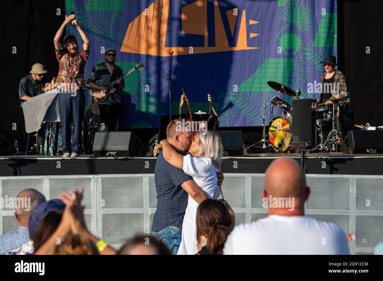Engagement couple kissing in front of Samuli Putro and concert audience at CoolHead Brew Viikki in Helsinki, Finland Stock Photo