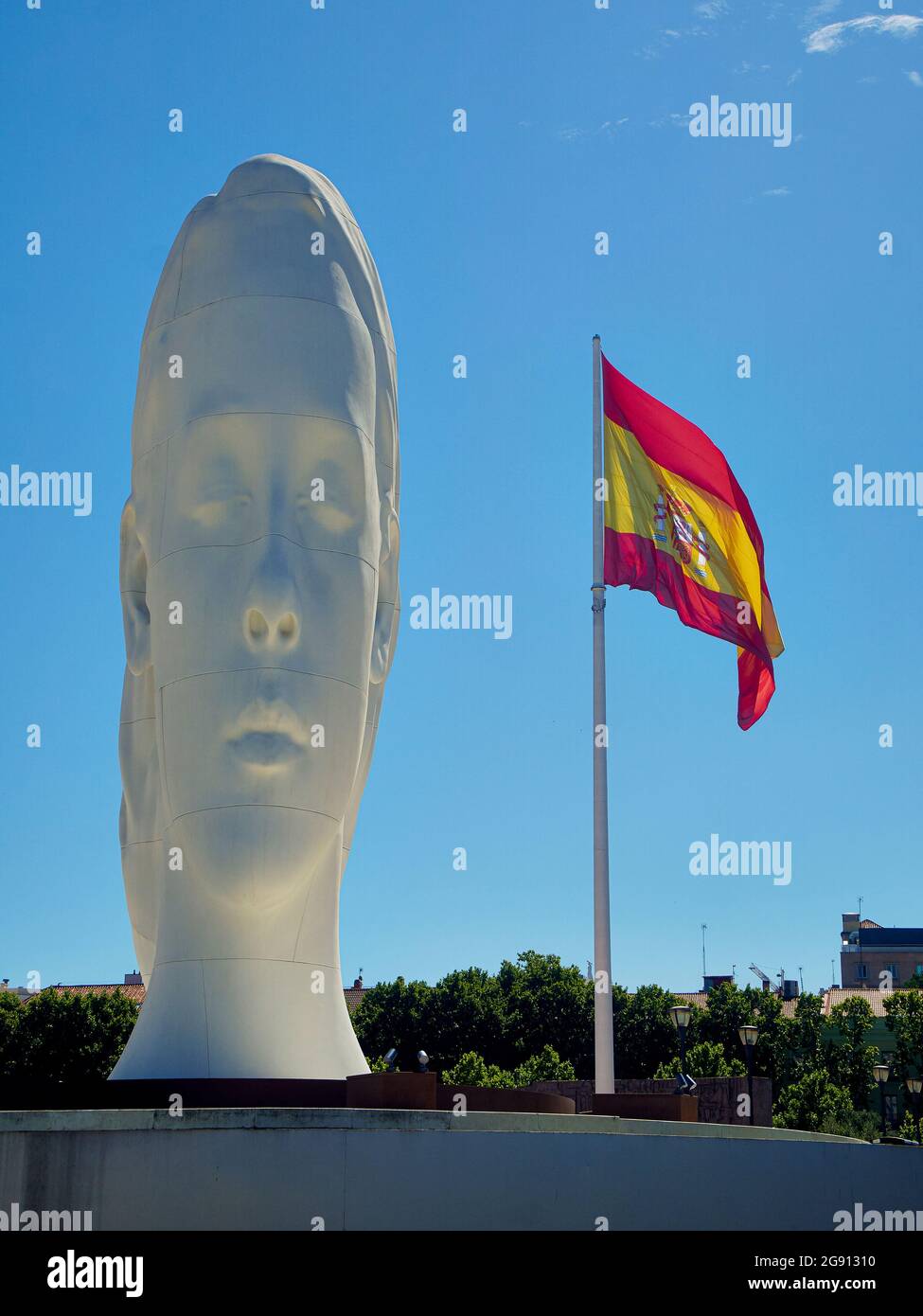 Madrid, Spain - July 12, 2021. Julia, a sculpture by Jaume Plensa with the Spanish flag in the background. Plaza de Colon square. Madrid, Spain. Stock Photo