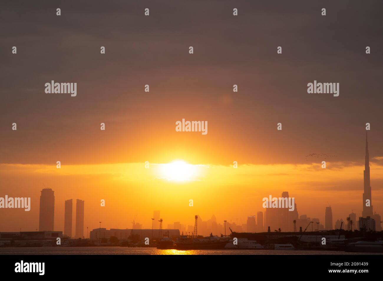 The Dubai skyline with Burj Khalifa at sunset as seen across the creek from Festival City. Dubai, UAE. Stock Photo