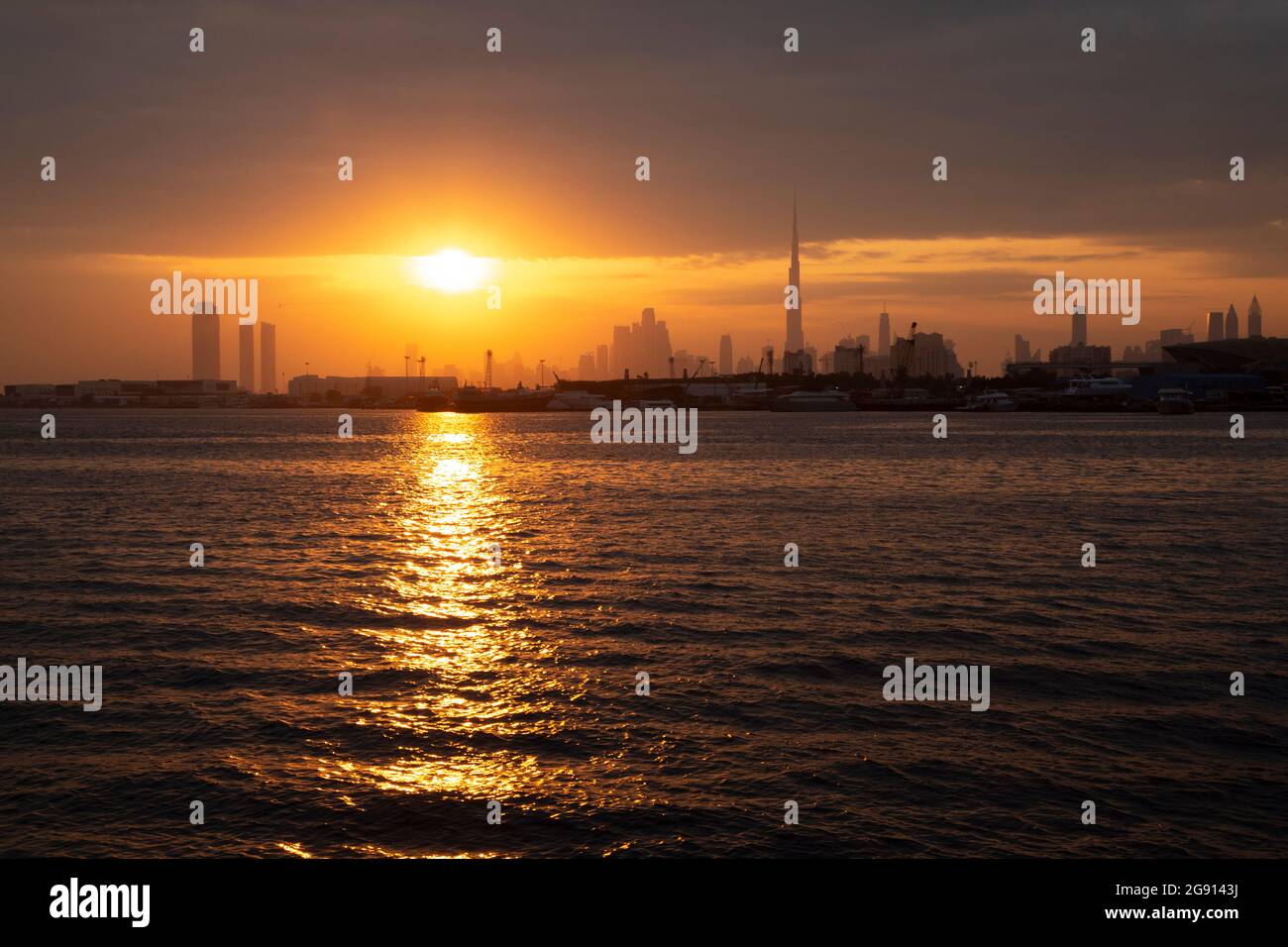 The Dubai skyline with Burj Khalifa at sunset as seen across the creek from Festival City. Dubai, UAE. Stock Photo