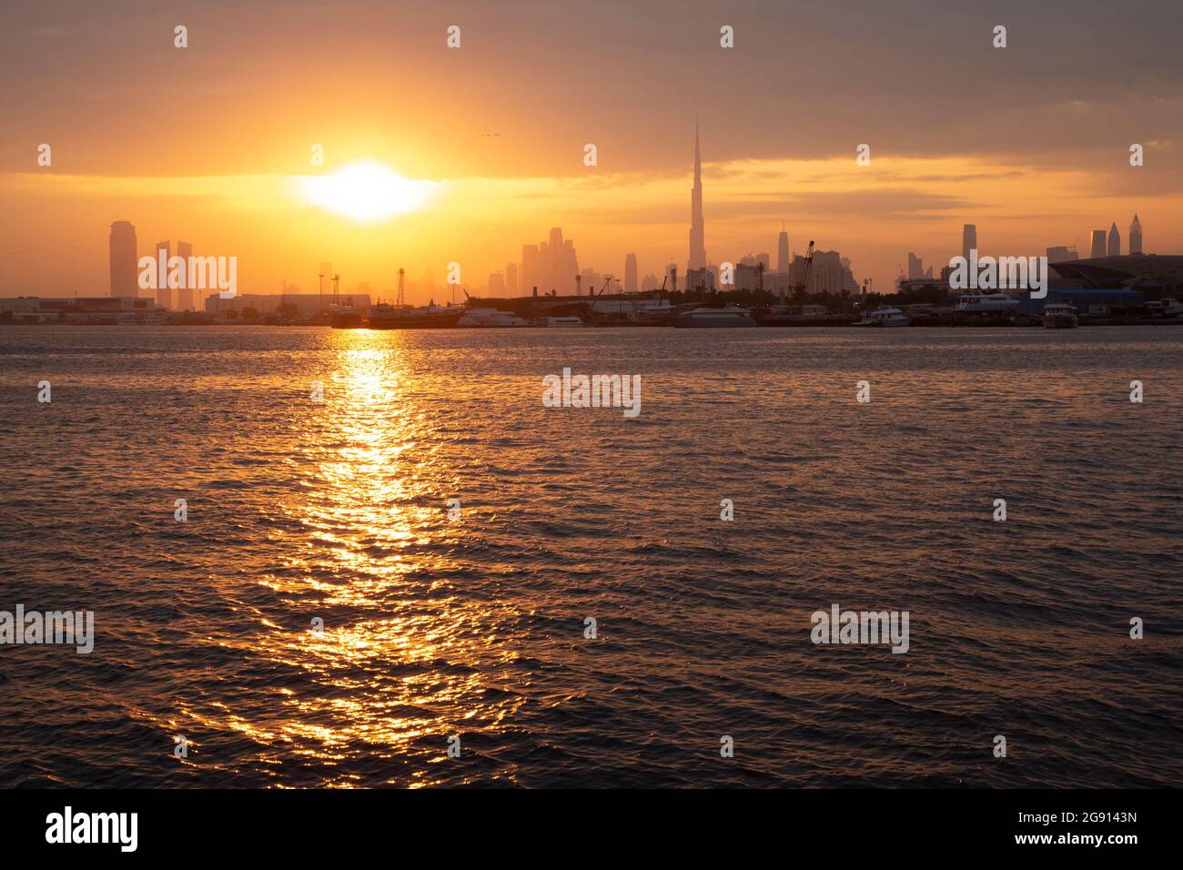 The Dubai skyline with Burj Khalifa at sunset as seen across the creek from Festival City. Dubai, UAE. Stock Photo