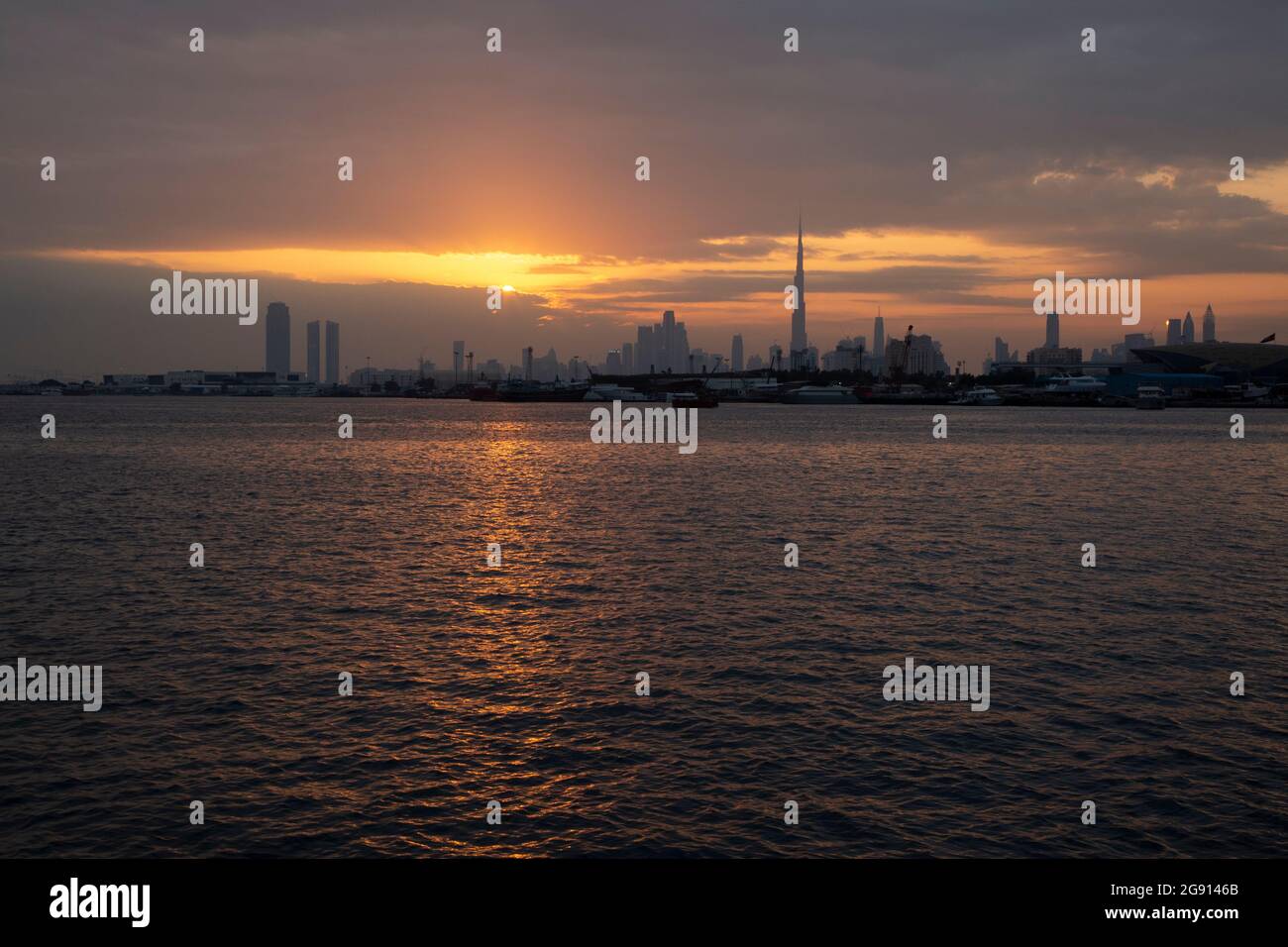 The Dubai skyline with Burj Khalifa at sunset as seen across the creek from Festival City. Dubai, UAE. Stock Photo