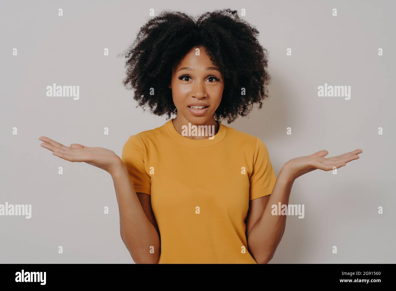 Confused doubtful black woman shrugging with shoulders, feeling baffled while looking at camera
