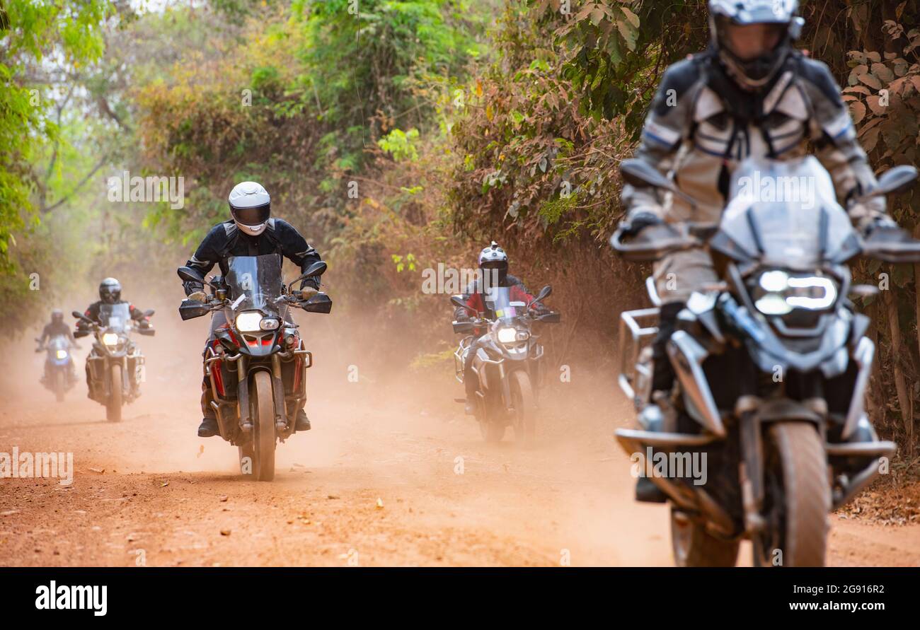 Group of men riding their adventure motorbike on dirt road in Cambodia