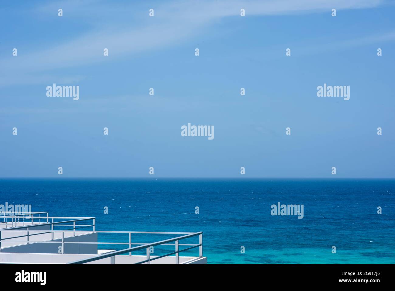 Metal railings on the roof of a building facing the Caribbean ocean. In the background the sea and the blue sky of the Mexican Caribbean. Stock Photo