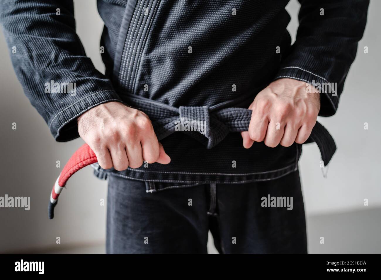 Front view of hands of unknown caucasian man in kimono gi standing while holding and tie knot