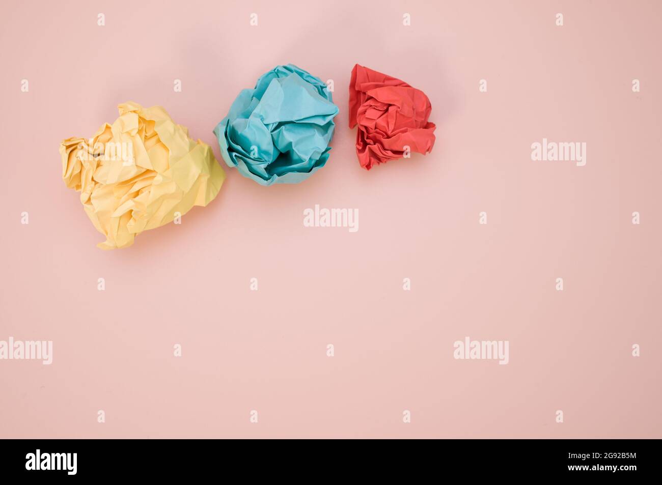 Closeup shot of aligned crumpled colored paper isolated on a pink background with copyspace Stock Photo