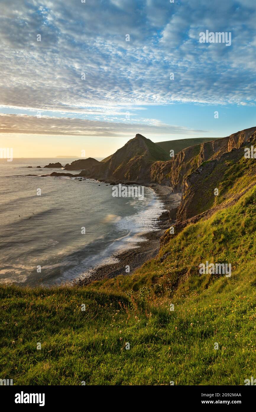 The low sunlight catches St Catherine's Tor on the North Devon coast. Hartland Quay with distant view of Lundy Island Stock Photo
