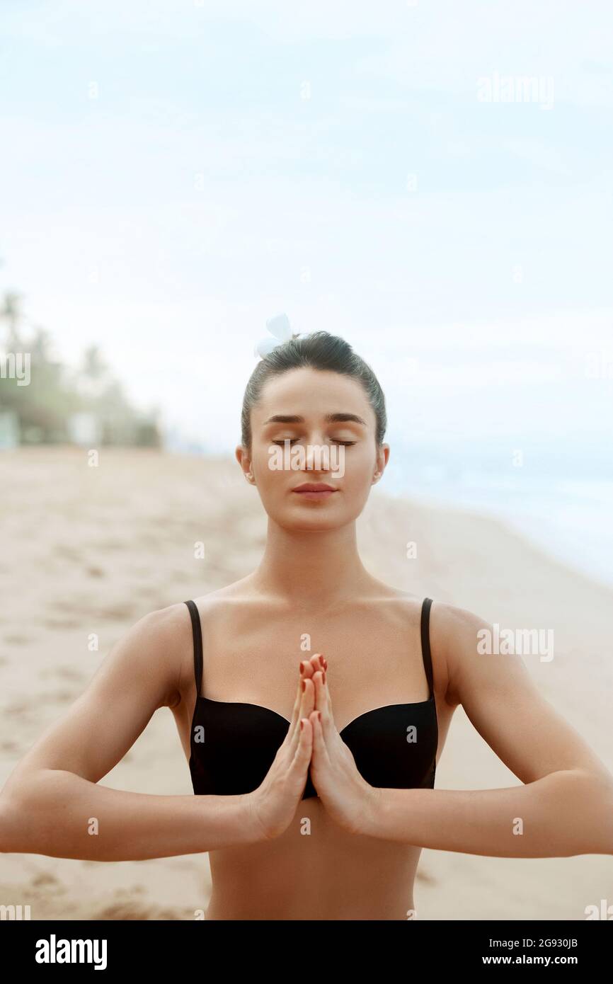 Beautiful woman practices yoga and meditates in the lotus position on th ebeach. Girl doing yoga.  Active Lifestyle. Healthy and yoga concept. Stock Photo